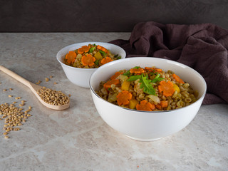 Porridge is spread out in two white bowls and decorated with a carrot-star, diet food.