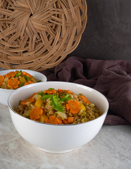 Spelt porridge in a white bowl and decorated with an asterisk carrot, diet food, PP concept. Brown background.