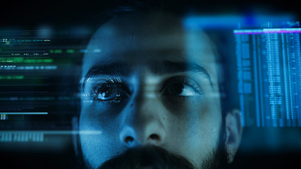 A close up of a young man eye controlling a futuristic computer system. Computer programmer coding on futuristic holographic display.