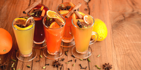 Five glasses of hot red mulled wine with fruit and spices, mango martini on table on orange background. Copy space.