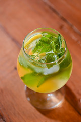 Classic fresh mojito on the table in a bar. Alcohol cocktail with ice, mint and lime on table with blurred background.
