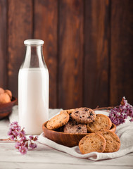 Chocolate chip cookies with milk on burlap and rustic wooden table