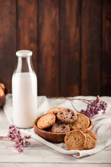 Chocolate chip cookies with milk on burlap and rustic wooden table