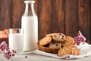 Chocolate chip cookies with milk on burlap and rustic wooden table