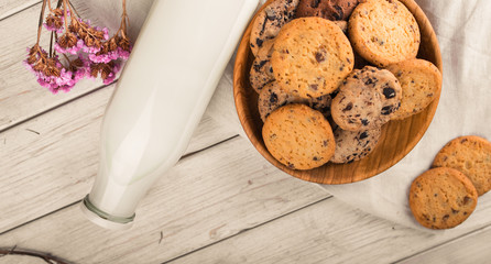 Chocolate chip cookies with milk on burlap and rustic wooden table