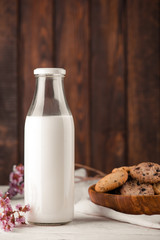 Chocolate chip cookies with milk on burlap and rustic wooden table