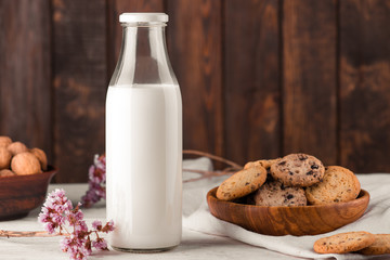 Chocolate chip cookies with milk on burlap and rustic wooden table