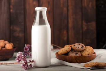 Chocolate chip cookies with milk on burlap and rustic wooden table