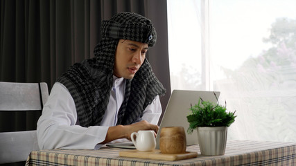 Young beautiful Asian Muslim man and women enjoying a relaxing moment in the coffee shop on a bright sunny day using mobile phone, smartwatch for mobile payment and QR code scan
