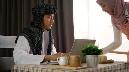 Young beautiful Asian Muslim man and women enjoying a relaxing moment in the coffee shop on a bright sunny day using mobile phone, smartwatch for mobile payment and QR code scan