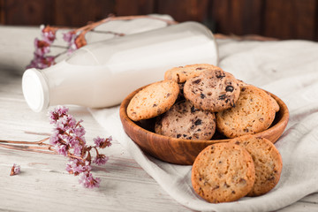 Chocolate chip cookies with milk on burlap and rustic wooden table