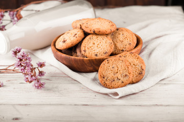 Chocolate chip cookies with milk on burlap and rustic wooden table