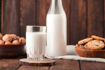 Chocolate chip cookies with milk on burlap and rustic wooden table