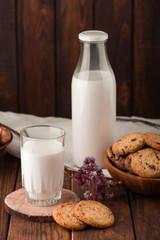 Chocolate chip cookies with milk on burlap and rustic wooden table