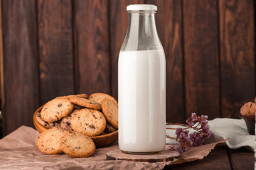 Chocolate chip cookies with milk on burlap and rustic wooden table