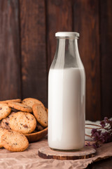 Chocolate chip cookies with milk on burlap and rustic wooden table