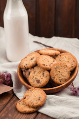 Chocolate chip cookies with milk on burlap and rustic wooden table