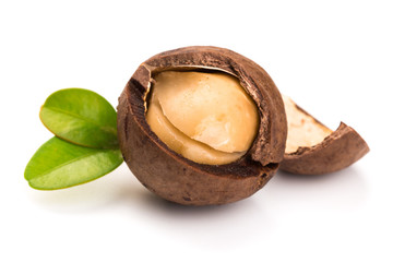 Macadamia nut with pieces and green leaves isolated on a white background