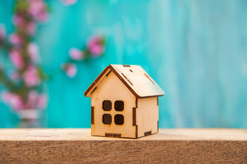 Obraz na płótnie Canvas Floral background for text and wooden house. Wooden table top with flowers close-up and copy space. Miniature house on a background of a blossoming tree in spring.