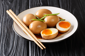 Delicious soft-boiled Japanese eggs nitamago in soya marinade with green onions close-up on the table. horizontal