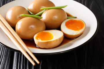Soft-boiled eggs of nitamago in soya marinade with green onions close-up in a plate. horizontal