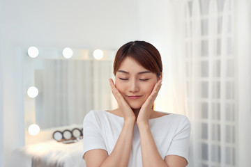 Attractive young Asian girl touching her face. Beauty & Skin care concept