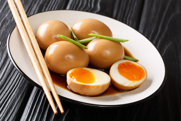 Nitamago ramen boiled eggs in soya marinade with green onions close-up in a plate. horizontal