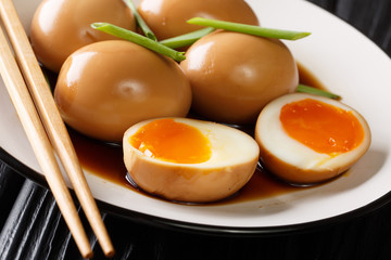 Nitamago is a boiled egg in savory sauce close-up in a plate on the table. horizontal