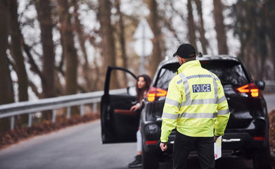 Male police officer in green uniform walking to the vehicle on the road