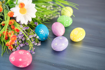 Fototapeta na wymiar Painted easter decoration with and flowers on gray wooden table.