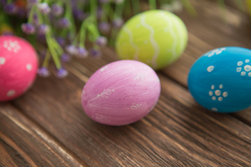 Obraz na płótnie Canvas Colorful easter eggs and flowers on rustic wooden planks