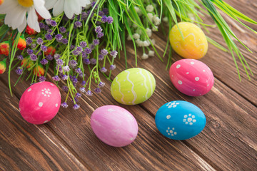 Obraz na płótnie Canvas Colorful pastel easter eggs with flowers on wooden board background