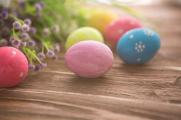 Fototapeta na wymiar Colorful easter eggs and flowers on rustic wooden planks
