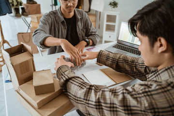 two young Asian workers work together to pack camera lenses in the office