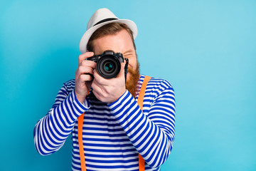 Portrait of positive cheerful man traveler use camera shoot picture visit voyage rest relax wear white vest nautical orange headwear isolated over blue color background