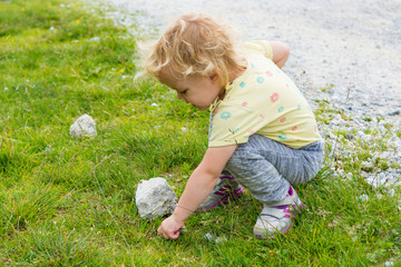 Cute blonde girl exploring green mountain pasture.