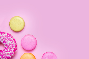 Seamless pattern made of macaroons and donut on the pink background. Flat lay. Food concept.