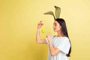 Egg hunt coming. Caucasian woman as an Easter bunny on yellow studio background. Happy easter...