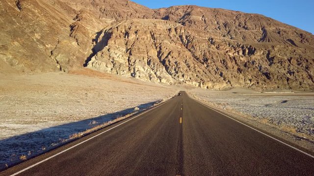 The lane of endless straight Badwater Road running through the barren scenery of famous Death Valley, California. It is one of the hottest places in the world.
