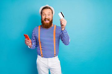 Red hair amazed crazy man use smart phone hold deposit card want pay buy service wear white shorts...