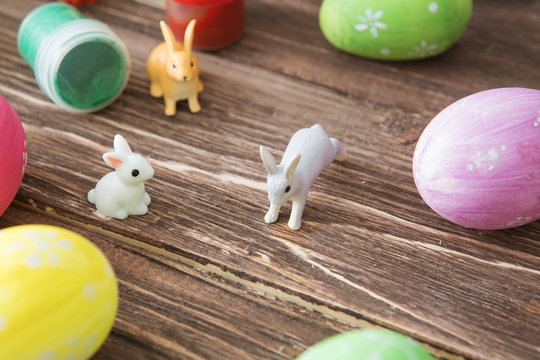 Easter eggs and Easter rabbits toys with flower on wooden table.
