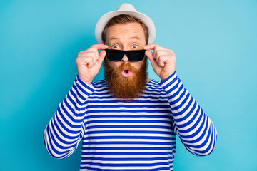 Portrait of astonished ginger hair man touch his sun specs enjoy journey look unbelievable promo impressed scream wear nautical outfit isolated over blue color background - obrazy, fototapety, plakaty