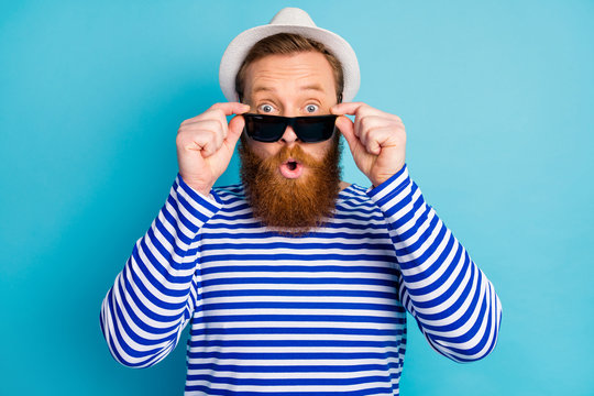Portrait of astonished ginger hair man touch his sun specs enjoy journey look unbelievable promo impressed scream wear nautical outfit isolated over blue color background