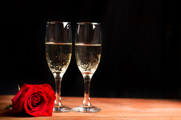  champagne glasses and rose on a black background