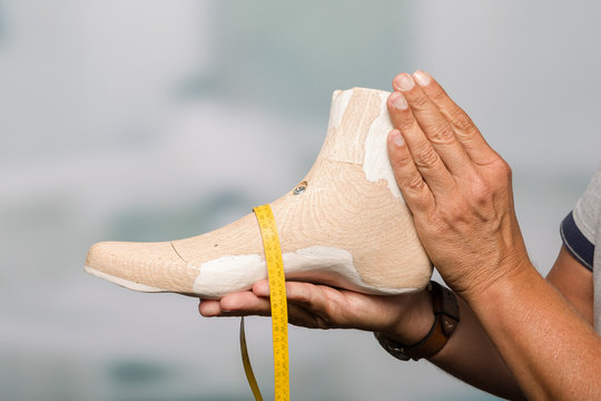 close up of hand of a orthopedic shoemaker presenting an individual crafted wooden last - Powered by Adobe
