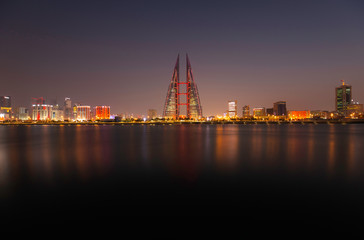 Panoramic view of Bahrain skyline at night with iconic buildings and dramatic reflection