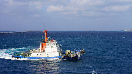 bright sea tug in the port of the Japanese city of Naha. Powerful industrial tugboat on a sunny day...