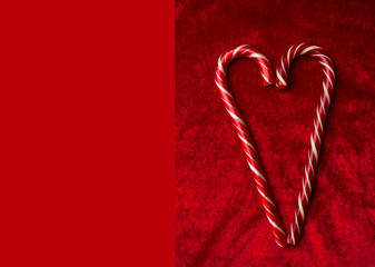 candy canes making a heart on a red velvet background, Christmas or Valentines day greeting card, love concept, copy space