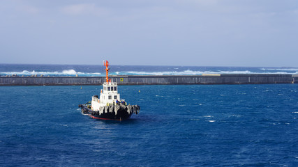  White towing ship in the ocean. A floating tow boat against a background of blue water and a clear...