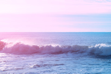 Calm beautiful sea in the early morning in the rays of the rising sun and a wave rolling ashore.